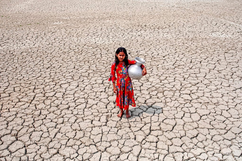 A girl walks on a drought-affected field after collecting drinking water from a pond in the nearby Sundarban mangrove forest in Satkhira, Bangladesh on March 27, 2022. Photo: Getty Images