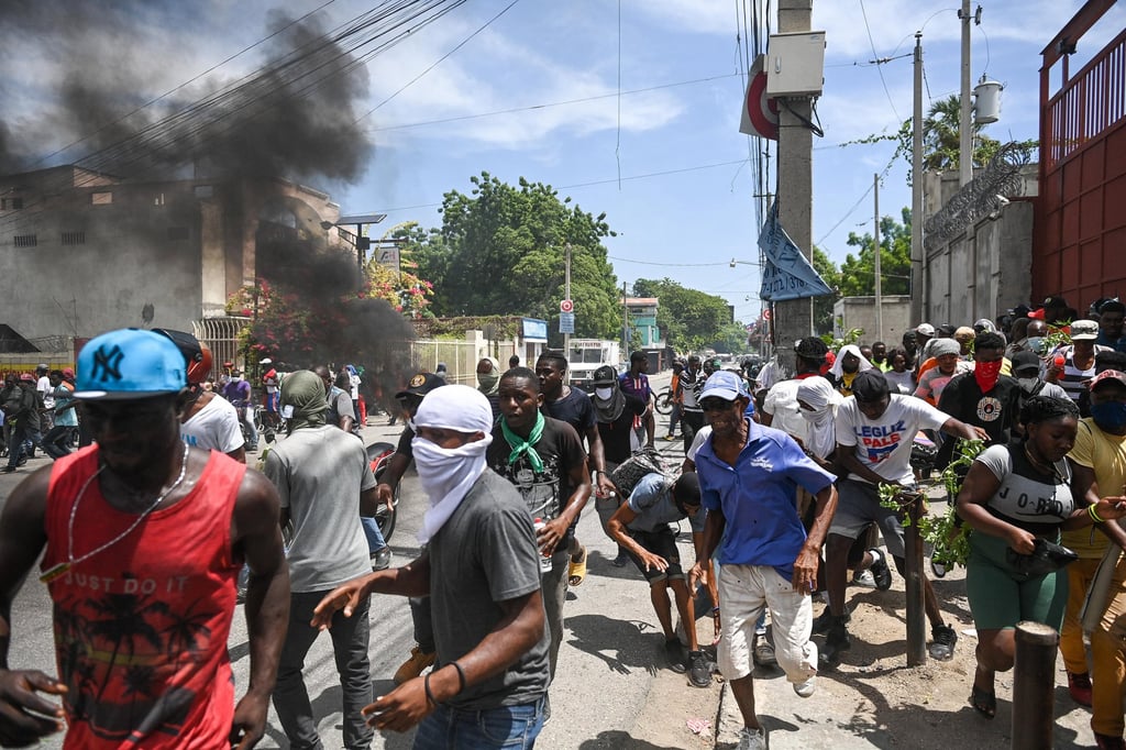 People in Port-au-Prince, Haiti, run for cover from tear gas fired by police during a protest against insecurity. Photo: TNS