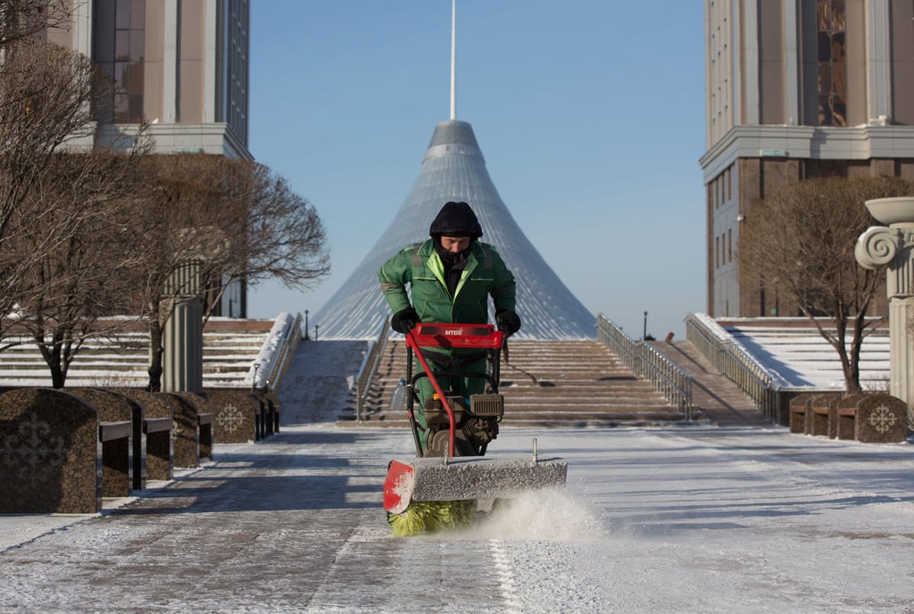 A municipal worker clears snow in Astana with the Khan Shatyr shopping centre in the background. Many migrants have flocked to Kazakhstan’s main cities, Almaty and Astana, contributing to a booming real-estate market. Photo: Bloomberg