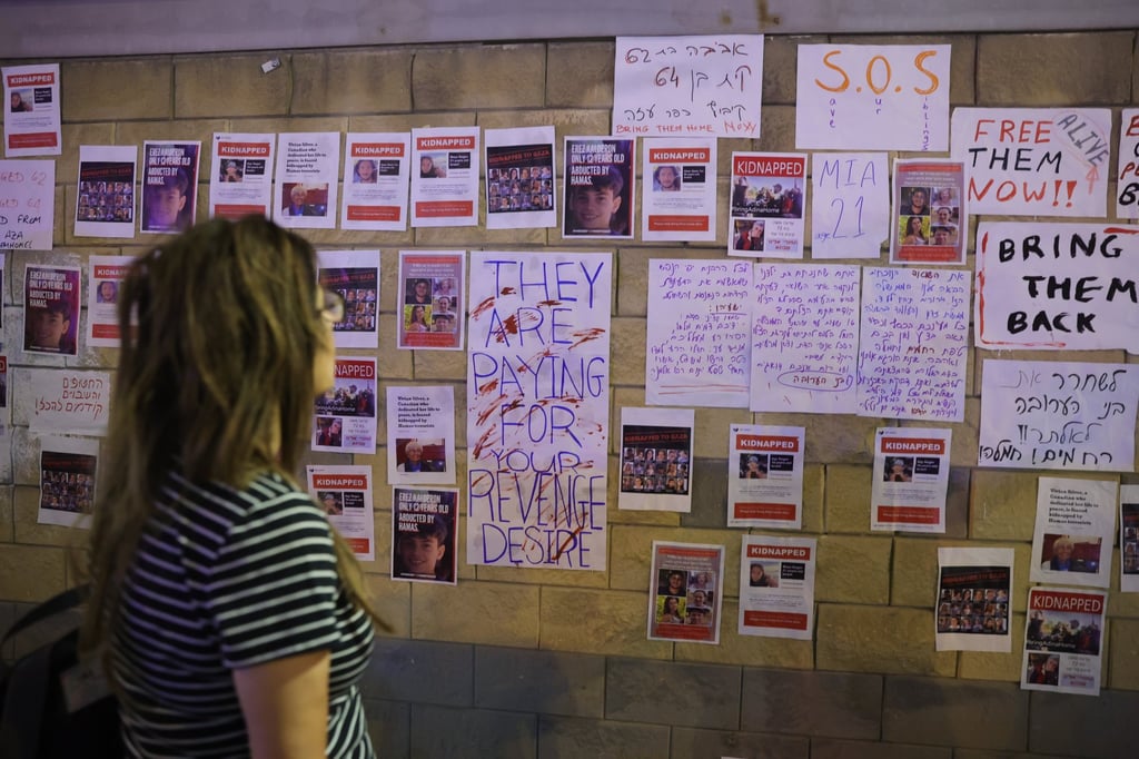 A woman looks at pictures of hostages held by Hamas militants in Gaza hanging on a wall outside a military base in Tel Aviv, Israel, on Saturday. Photo: EPA-EFE