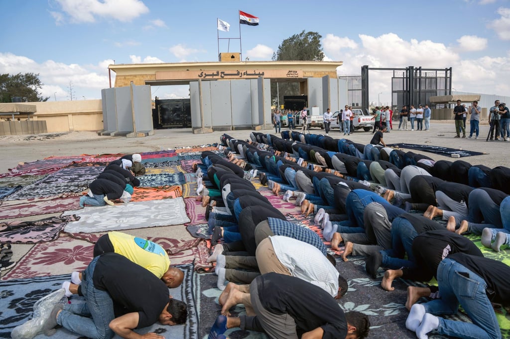 Volunteers from humanitarian aid organisations pray outside Rafah border gate in Egypt on Wednesday. Photo: EPA-EFE Volunteers from humanitarian aid organisations pray outside Rafah border gate in Egypt on Wednesday. Photo: EPA-EFE