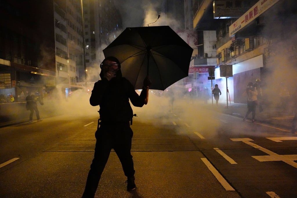 A protester holds an umbrella as police fire tear gas during a demonstration in Hong Kong on January 1, 2020. Photo: AP A protester holds an umbrella as police fire tear gas during a demonstration in Hong Kong on January 1, 2020. Photo: AP