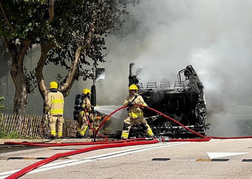 Firefighters clear up around the charred remains of a burned-out bus in Discovery Bay. Photo: Facebook/Brandon Wong