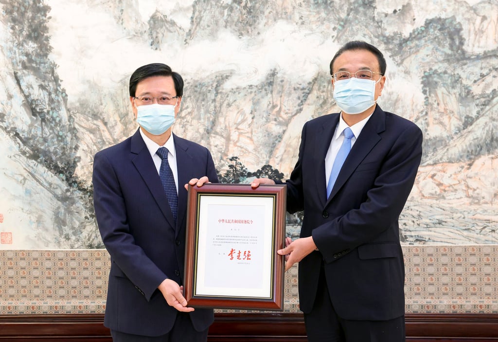 John Lee (left) receives his formal letter of appointment from Li Keqiang. Photo: Xinhua