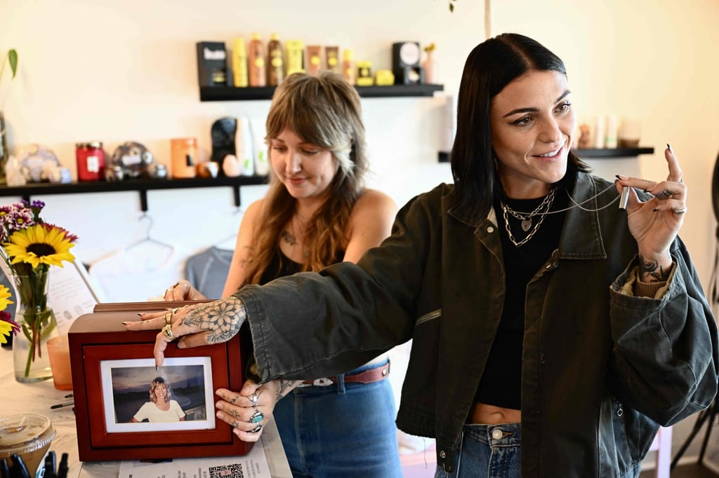 Scout Frank (right) talks about the ashes of her cremated mother, Theresa Pendleton, before receiving a hand poke tattoo from artist Kat Dukes (rear) using ink mixed with the ashes in Oceanside, California. Photo: AFP Scout Frank (right) talks about the ashes of her cremated mother, Theresa Pendleton, before receiving a hand poke tattoo from artist Kat Dukes (rear) using ink mixed with the ashes in Oceanside, California. Photo: AFP