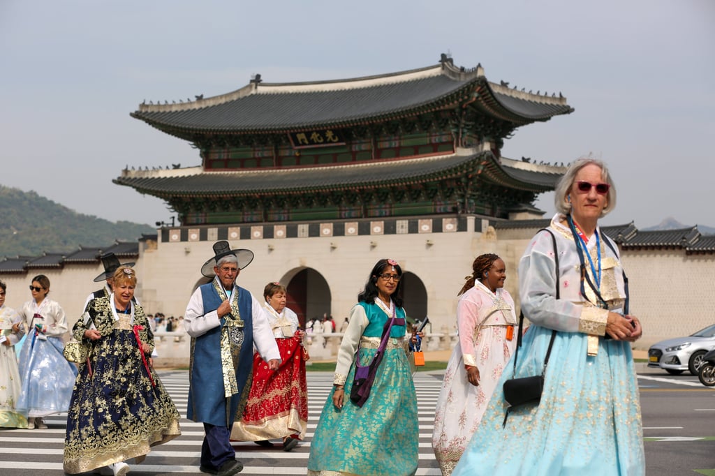 Tourists wearing traditional Korean hanbok cross a street near Gwanghwamun, the largest gate of Gyeongbokgung Palace in Seoul. Photo: Xinhua