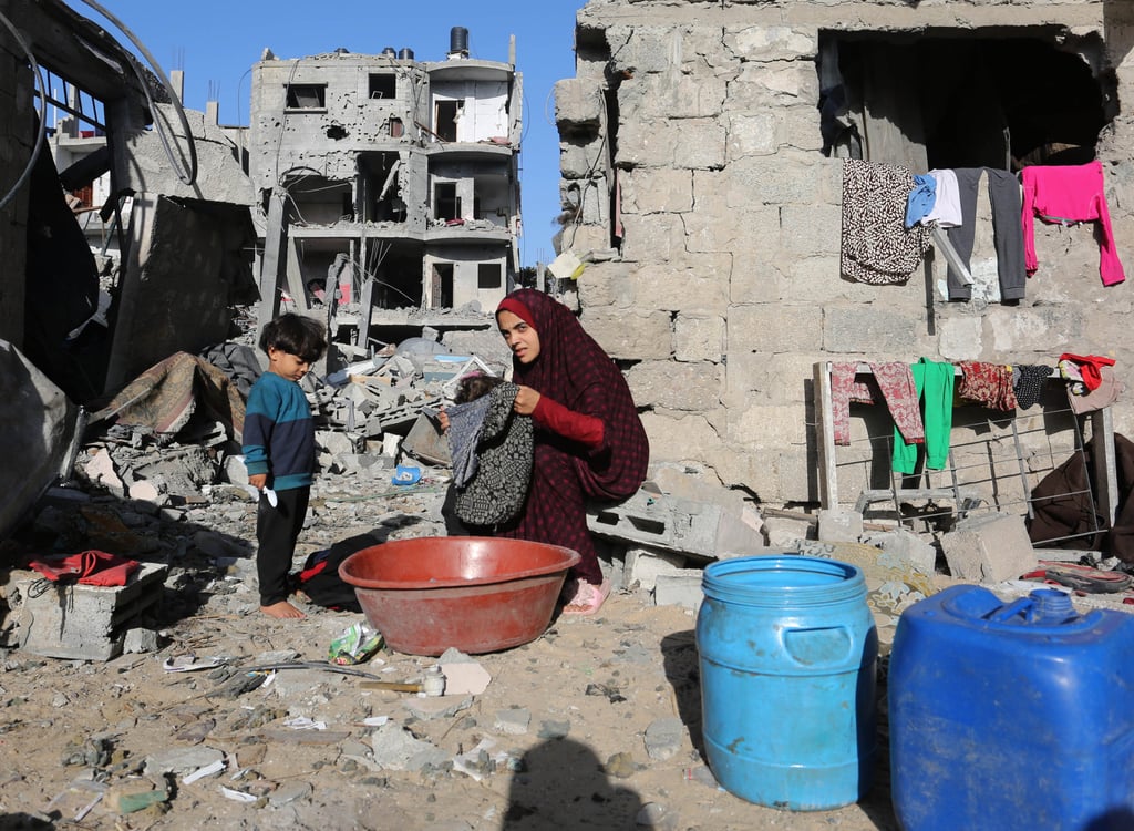 A woman does household chores among the rubble of buildings destroyed in Israeli air strikes in the southern Gaza Strip city of Rafah. Photo: Xinhua