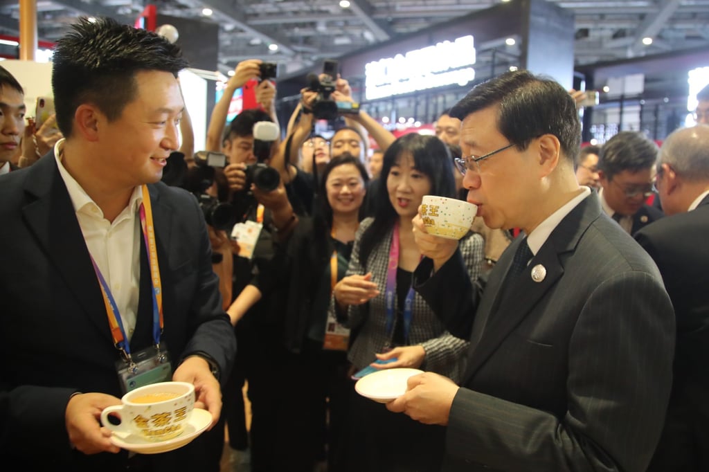 Chief Executive John Lee Ka-chiu (right) seen siping tea while chatting with a representative of a Hong Kong exhibitor at the China International Import Expo in Shanghai on November 5, 2023. Photo: Daniel Ren