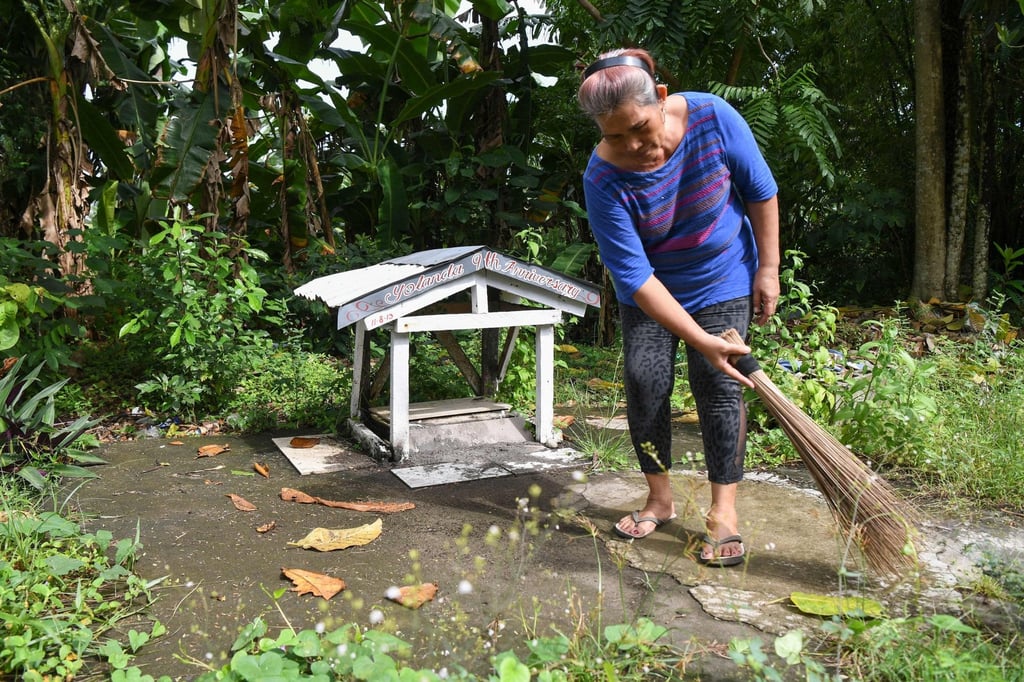 Agatha Ando, a survivor of Super Typhoon Haiyan, sweeps her family’s mass grave in front of her house in Tacloban city’s San Jose district, Leyte province. Photo: AFP Agatha Ando, a survivor of Super Typhoon Haiyan, sweeps her family’s mass grave in front of her house in Tacloban city’s San Jose district, Leyte province. Photo: AFP
