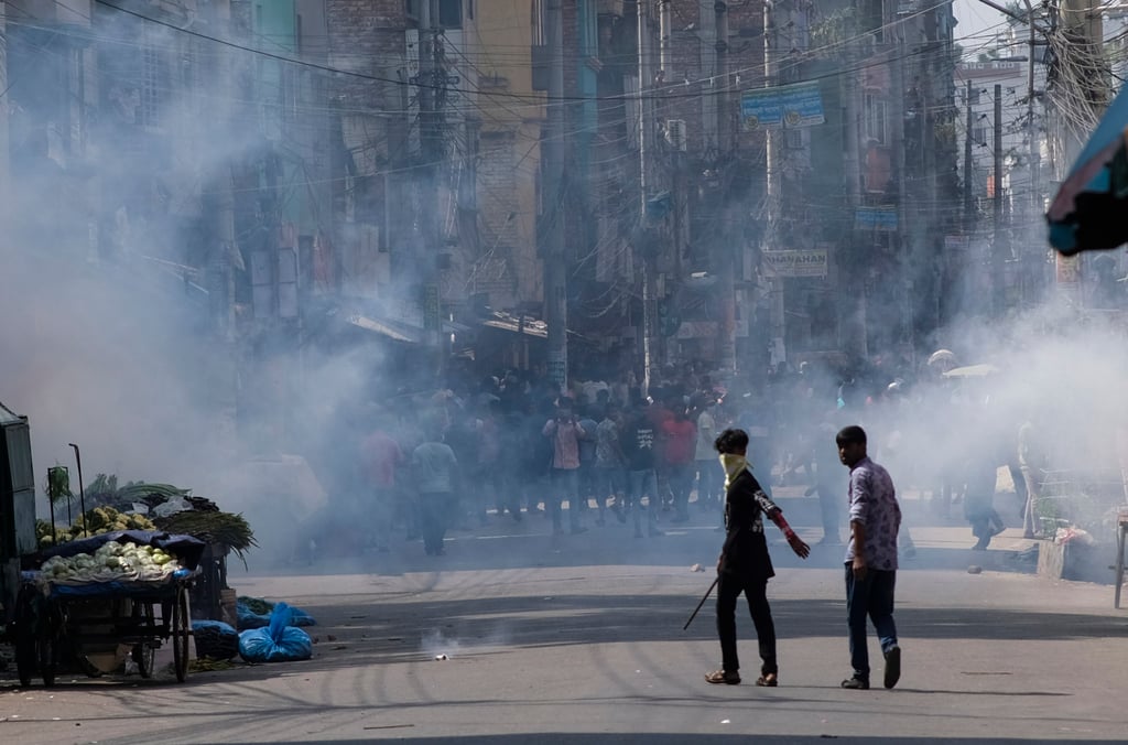 Police fire tear gas shells to disperse Bangladeshi garment factory workers who were blocking traffic demanding better wages. Photo: AP Police fire tear gas shells to disperse Bangladeshi garment factory workers who were blocking traffic demanding better wages. Photo: AP