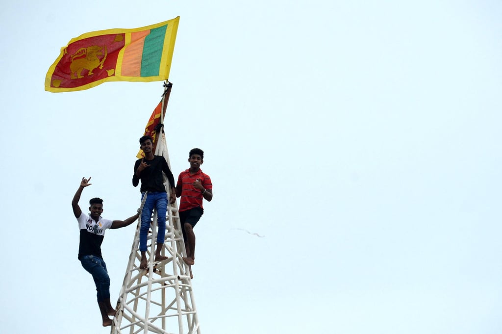 A man waves Sri Lanka’s national flag after climbing a tower near presidential secretariat in Colombo. Photo: AFP