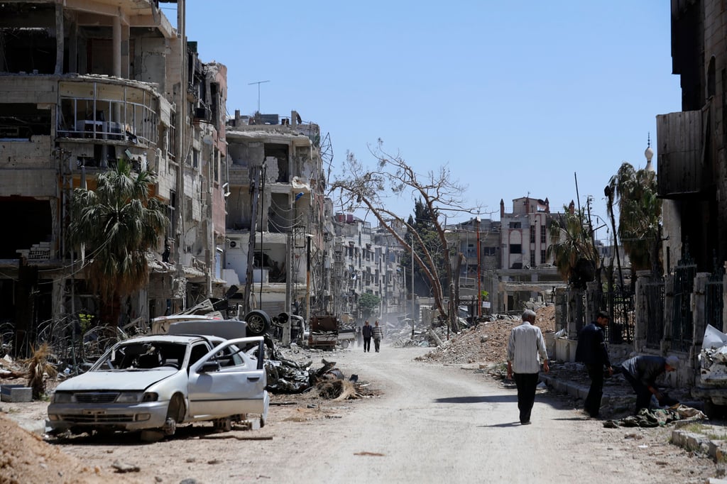 Syrians walk through destruction in the town of Douma, the site of a suspected chemical weapons attack, near Damascus, Syria in April 2018. Photo: AP