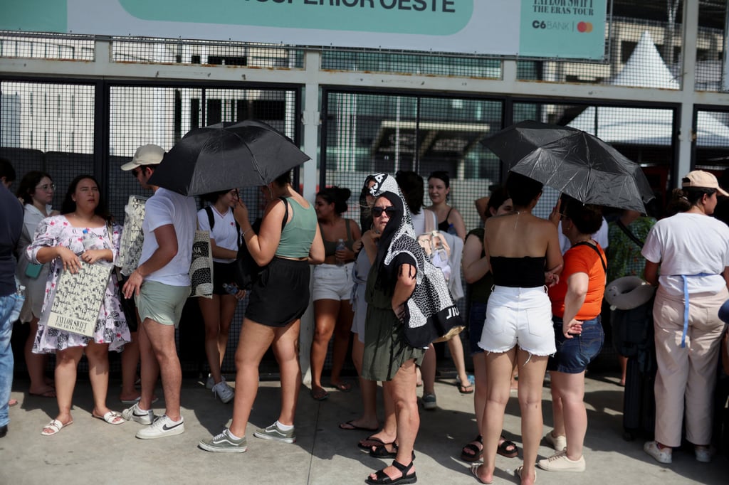 Women protect themselves from the sun as they stand in a queue outside the stadium for the Taylor Swift concert. Photo: Reuters