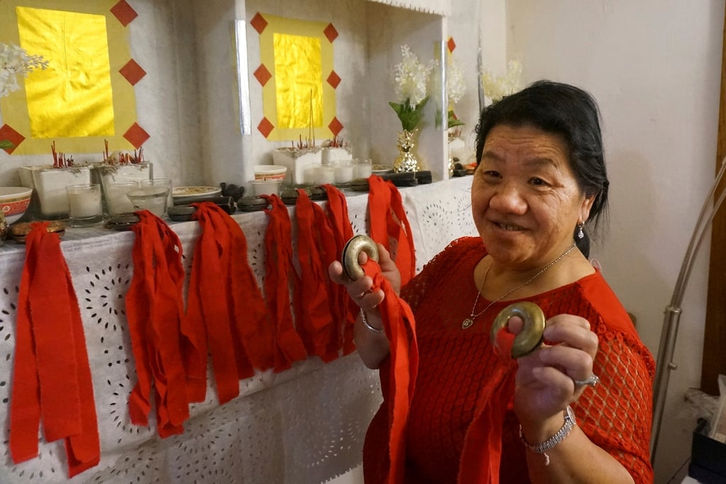 Mee Vang Yang holds her father’s ring-shaped shaman bells in front of the altar in her living room in St Paul, Minnesota. Photo: AP