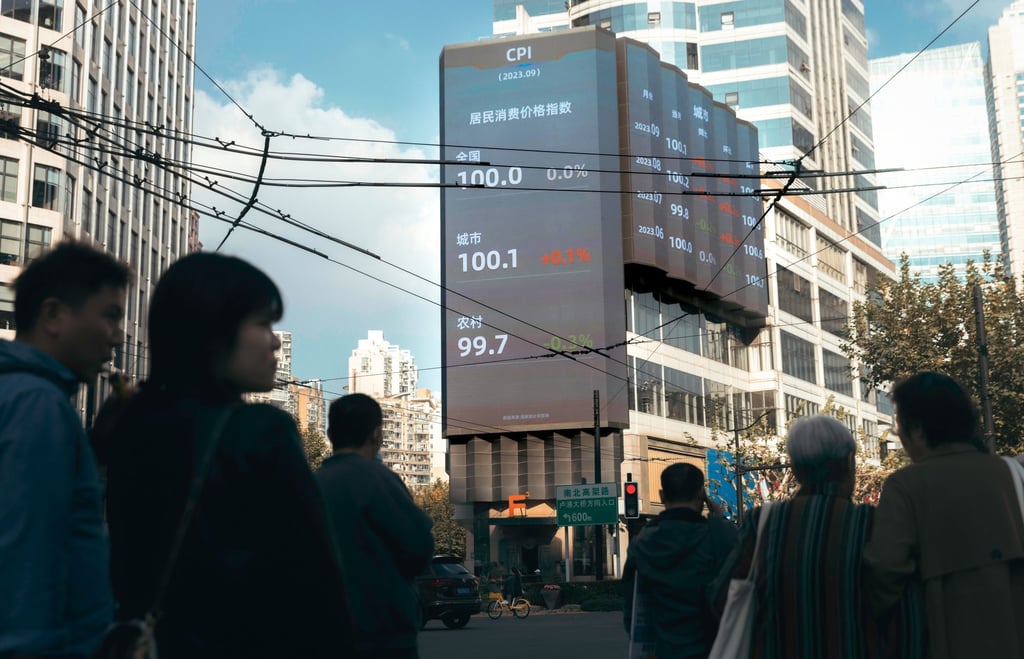 People stand on the street beneath a large screen showing the latest stock exchange and economy data, in Shanghai, China. Photo: EPA-EFE