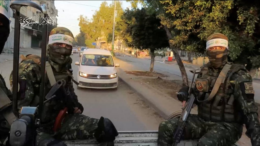 Hamas members sit as hostages are handed over to the International Red Cross in the Gaza Strip on Thursday. Photo: Hamas Military Wing via Reuters