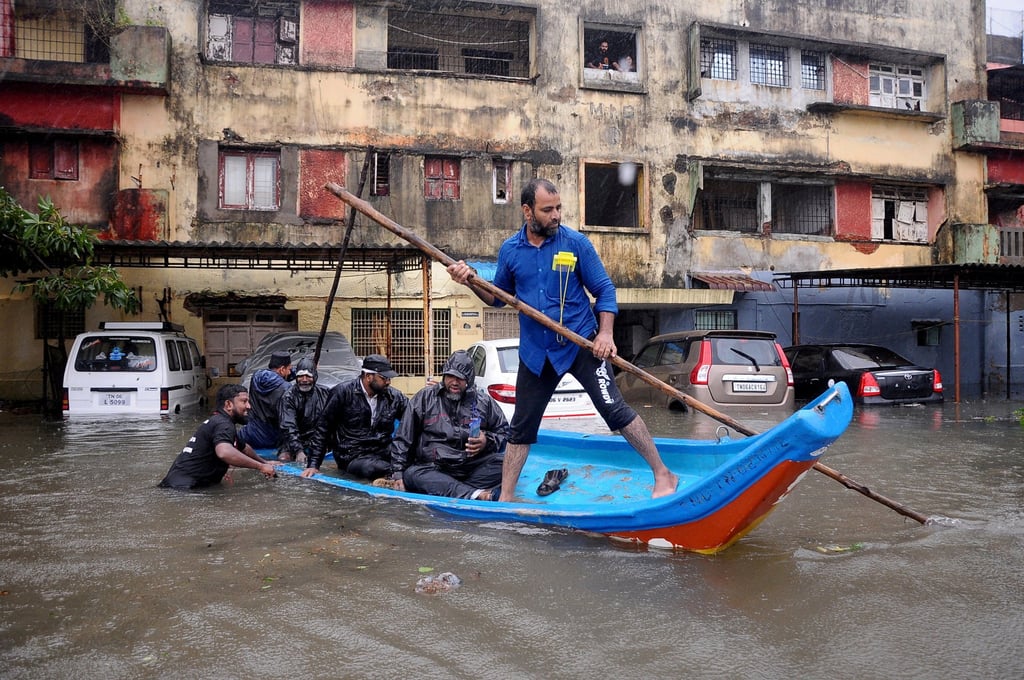 People move in a boat past partially submerged vehicles in a residential area following heavy rains ahead of Cyclone Michaung in Chennai, India. Photo: Reuters