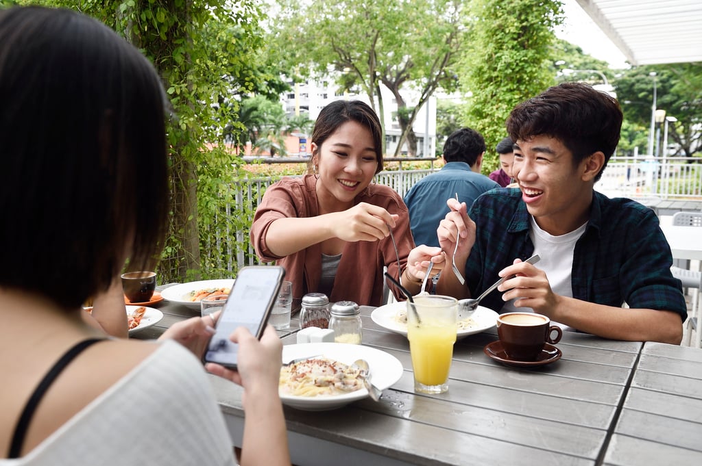 A diner photographs her food at a cafe in Singapore. Posting on social media – not just scrolling through feeds for information on destinations – is popular with younger travellers. Photo: Getty Images