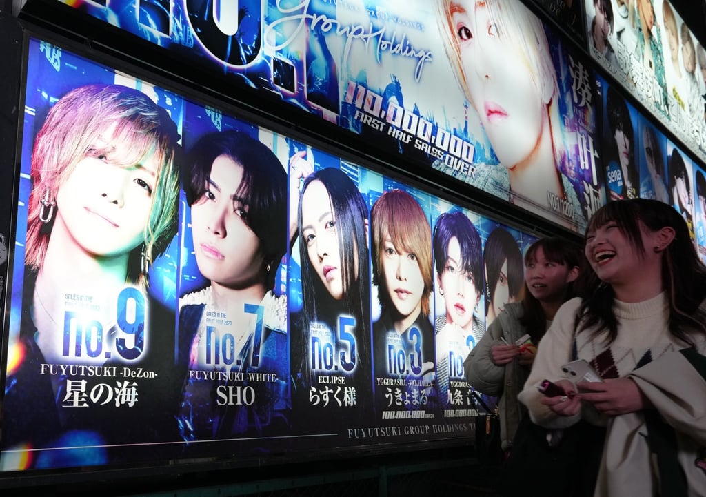 Women walk past a billboard of a host club at Kabukicho in Tokyo’s Shinjuku district. Photo: EPA-EFE