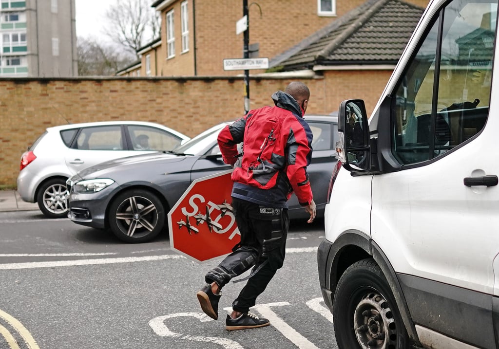 A man runs away with a traffic sign with art from Banksy in London on Friday. Photo: PA Wire via dpa