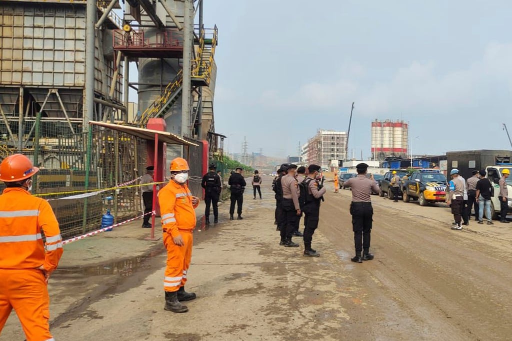 Police officers and workers stand near the site where a furnace explosion occurred at a nickel smelting plant in Indonesia. Photo: AP Police officers and workers stand near the site where a furnace explosion occurred at a nickel smelting plant in Indonesia. Photo: AP