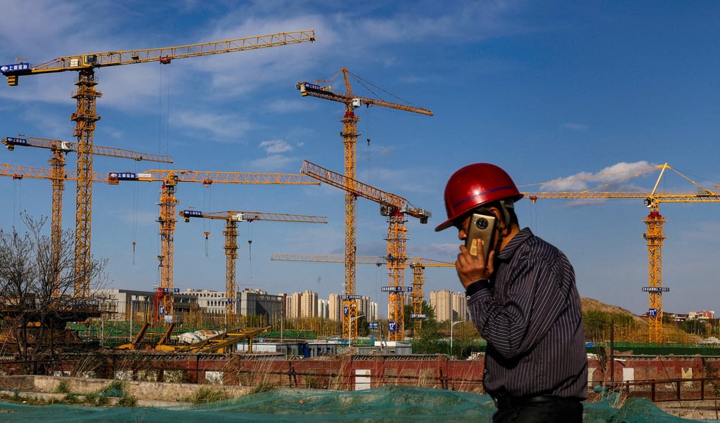 A worker speaking on his phone walks past a construction site in Beijing, China. Photo: Reuters