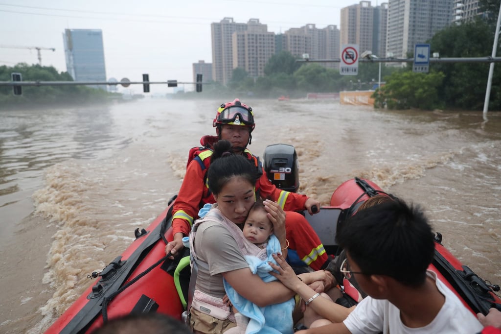 A woman holds a baby as rescuers evacuate residents stranded by floodwaters following heavy rainfall in Zhuozhou, Hebei province, China, on August 2, 2023. Photo: China Daily via Reuters