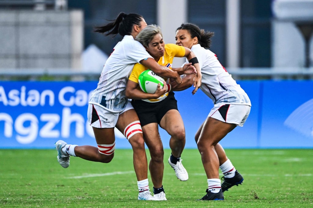 Thailand’s Thanachporn Wandee (centre) tries to fight her way through a double tackle by Hong Kong’s Chloe Chan (left) and Natasha Olson-Thorne at the Asian Games. Photo: AFP Thailand’s Thanachporn Wandee (centre) tries to fight her way through a double tackle by Hong Kong’s Chloe Chan (left) and Natasha Olson-Thorne at the Asian Games. Photo: AFP