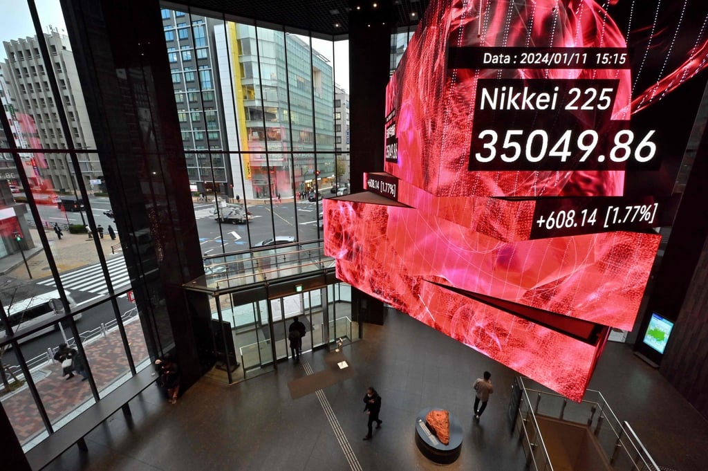 Pedestrians walk below a signboard showing the closing numbers on the Tokyo Stock Exchange, along a street in Tokyo on Thursday. Photo: AFP Pedestrians walk below a signboard showing the closing numbers on the Tokyo Stock Exchange, along a street in Tokyo on Thursday. Photo: AFP