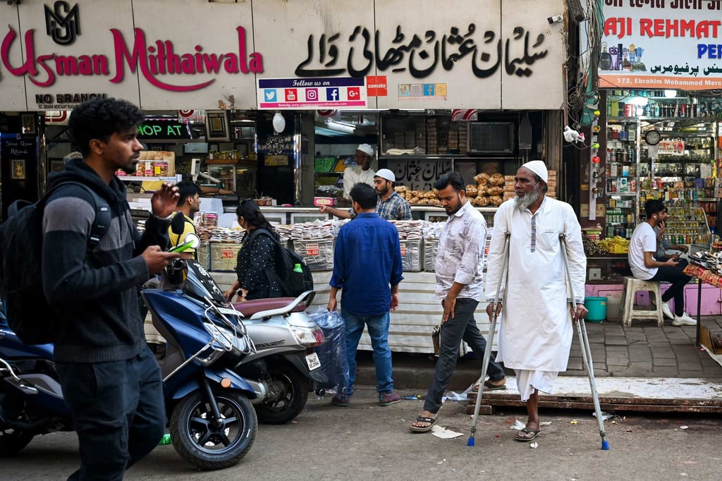 Pedestrians walk past shops along a crowded street near Minara Masjid mosque in Mumbai.