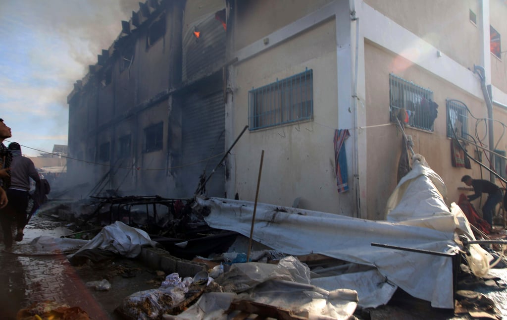 Palestinians try to extinguish a fire at a building of an UNRWA vocational training centre which displaced people use as a shelter, after being targeted by an Israeli tank in Khan Younis, southern Gaza Strip on Wednesday. Photo: AP