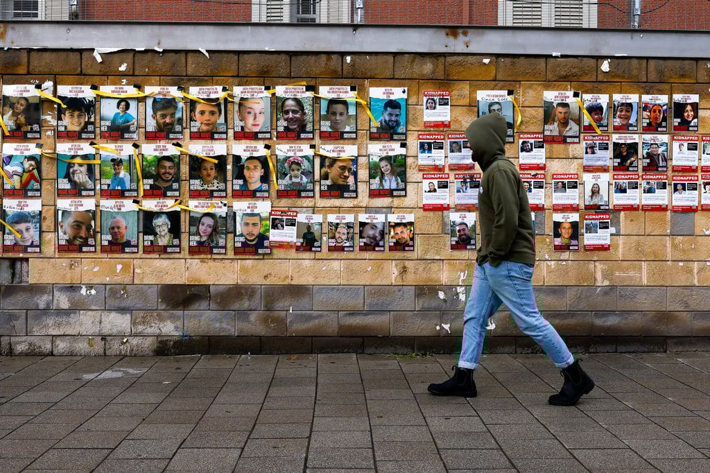 A person walks past a wall in Tel Aviv, Israel, on Friday, with pictures of hostages who were captured by Hamas on October 7. Photo: Reuters