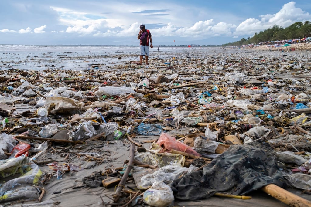 A man walks near rubbish that was washed ashore by strong waves at a beach in Kuta. Photo: EPA-EFE A man walks near rubbish that was washed ashore by strong waves at a beach in Kuta. Photo: EPA-EFE