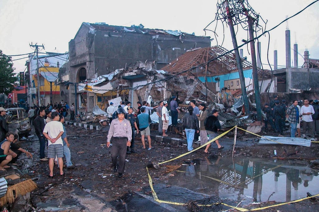 Police and onlookers at the site of a bomb blast on October 13, 2002, in the tourist area of Kuta in Bali, Indonesia where more than 200 people were killed. Photo: AFP