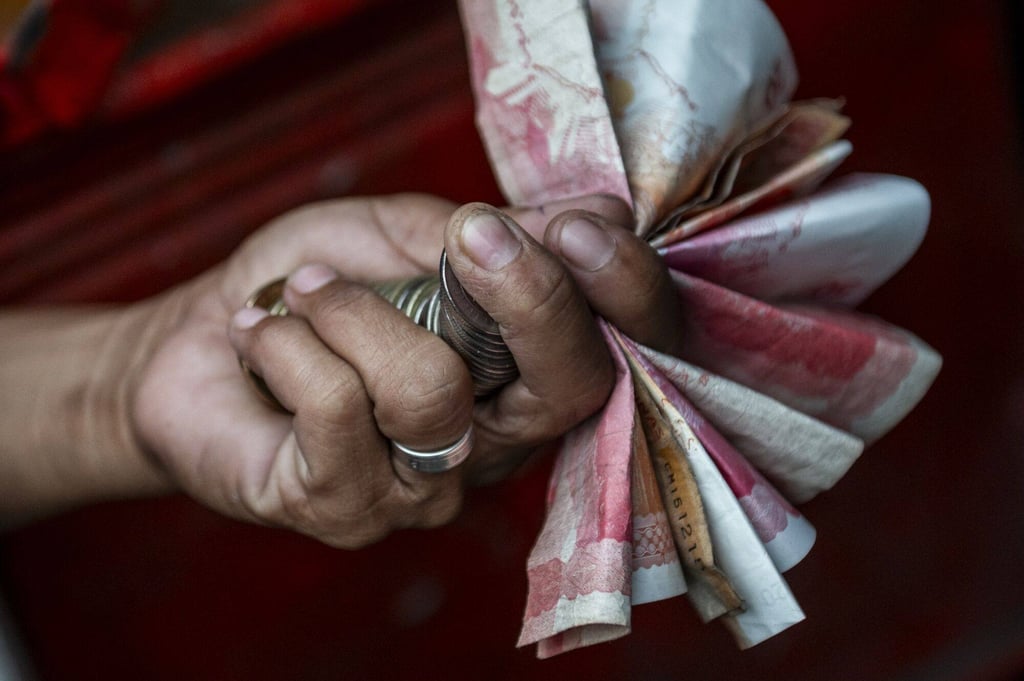 A conductor handles peso bills and coins in Caloocan City, the Philippines. Photo: Bloomberg A conductor handles peso bills and coins in Caloocan City, the Philippines. Photo: Bloomberg