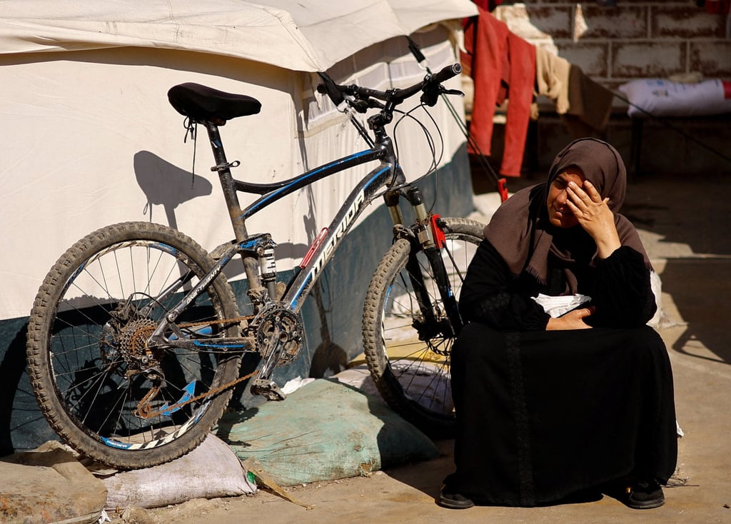 A displaced Palestinian woman sits by a tent while sheltering in a UNRWA school. Photo: Reuters