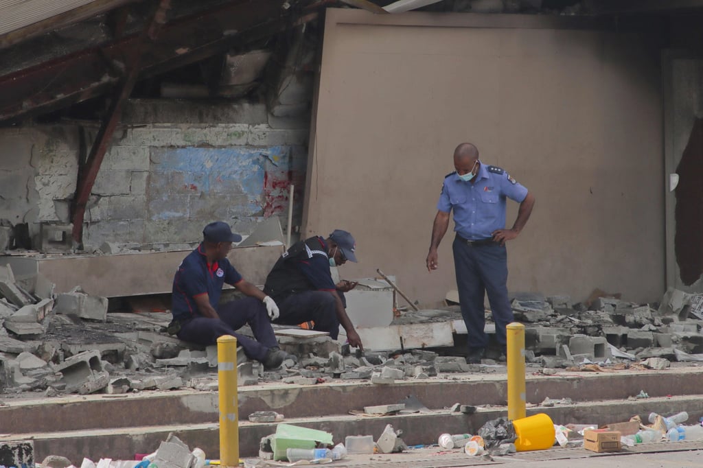 Police work at the site of a damaged building in Port Moresby after riots on January 12, 2023. Photo: AFP