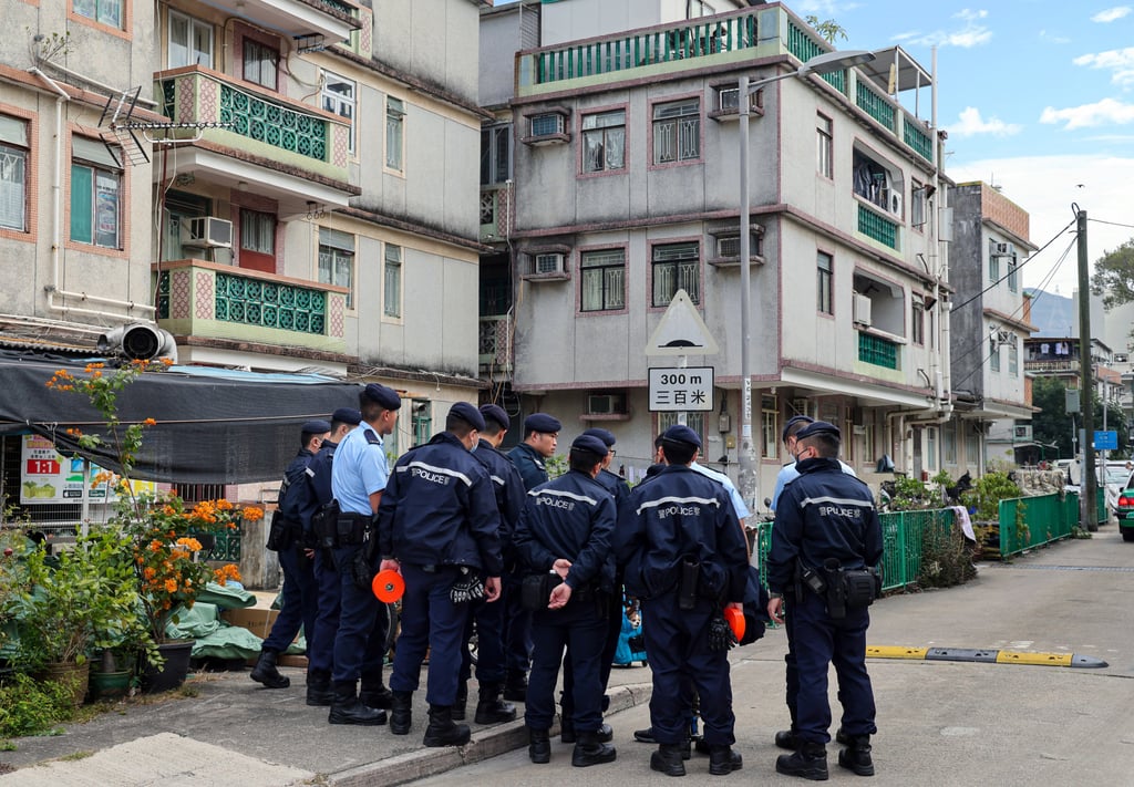 Police officers escort one of those arrested, Kwan Wing-yin, back to a flat in Fanling Wai, Sheung Shui for a re-enactment of the manslaughter case in December. Photo: Jelly Tse Police officers escort one of those arrested, Kwan Wing-yin, back to a flat in Fanling Wai, Sheung Shui for a re-enactment of the manslaughter case in December. Photo: Jelly Tse