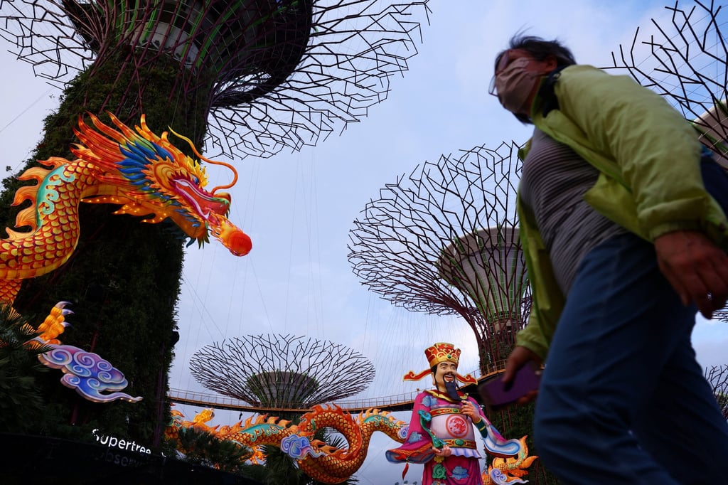 People pass the God of Fortune statue and dragon sculpture, as part of festive decorations welcoming the Lunar New Year 2024, Year of the Dragon, among the Supertrees at Gardens By The Bay in Singapore. Photo: Reuters