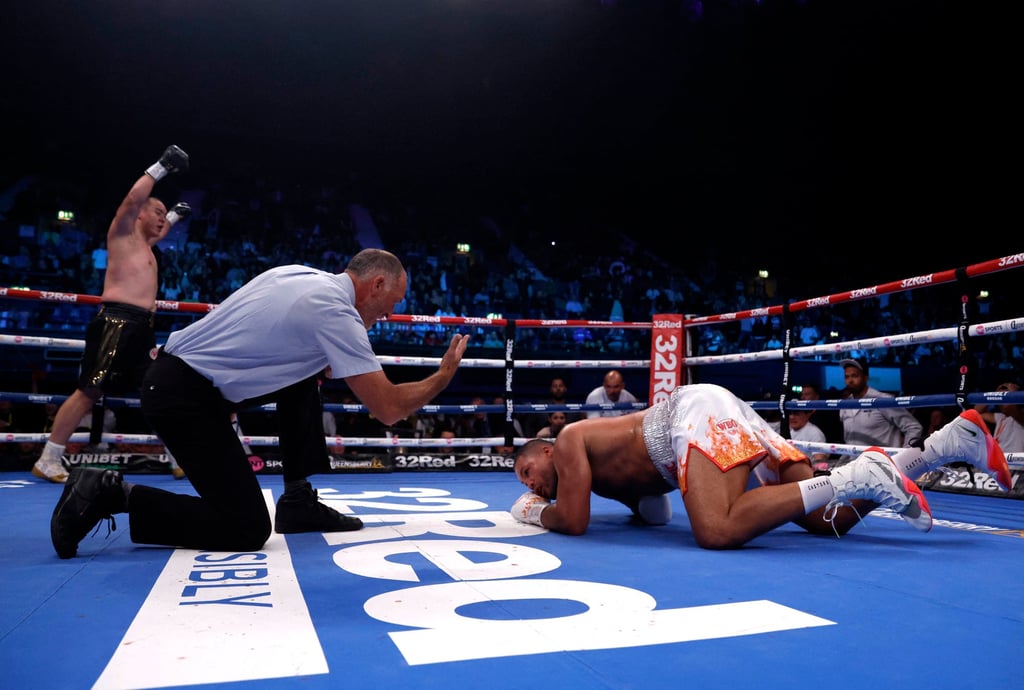 Joe Joyce (right) tries to get back up after being knocked down by Zhang Zhilei in their first title fight. Photo: Reuters