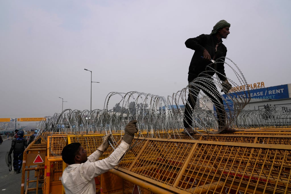 Workers put up barbed wire on top of barricades on a major highway at Singhu near New Delhi to stop thousands of protesting farmers from entering the capital. Photo: AP Workers put up barbed wire on top of barricades on a major highway at Singhu near New Delhi to stop thousands of protesting farmers from entering the capital. Photo: AP