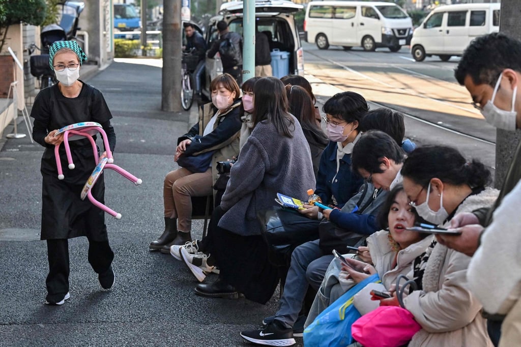 Ukon giving out small stools for queuing customers to sit on over an hour before Onigiri Bongo opens. Photo: AFP Ukon giving out small stools for queuing customers to sit on over an hour before Onigiri Bongo opens. Photo: AFP
