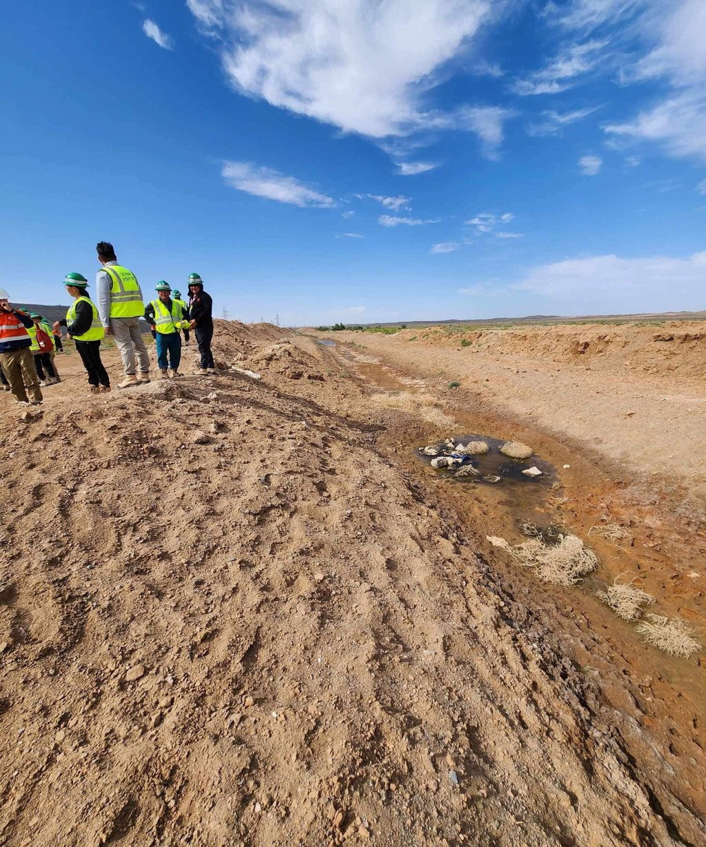 Workers stand near a trench collecting seepage water at Rio Tinto’s copper mine in Oyu Tolgoi, Mongolia, on July 25, 2023. The mining project has been blamed for wells going dry in the area, harming the livelihoods of traditional nomadic herders. Photo: Accountability Counsel/Reuters