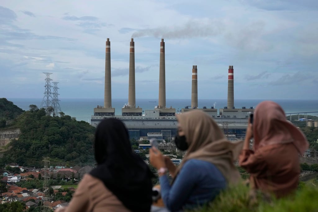 Indonesian women sit on a hill as the Suralaya coal power plant looms in the background in Cilegon, Indonesia, on January 8, 2023. Photo: AP