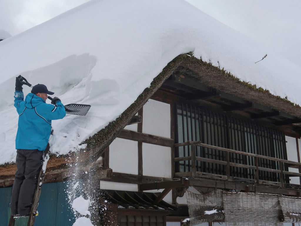 A resident clears snow from the roof of his home in Ouchi Juku, deep in the mountains of Fukushima prefecture, Japan. Photo: Julian Ryall