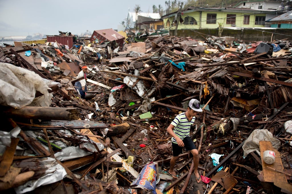 Victims of Super Typhoon Haiyan make their way along a road blocked by the rubble of destroyed homes in Tacloban City in 2013. Photo: AFP