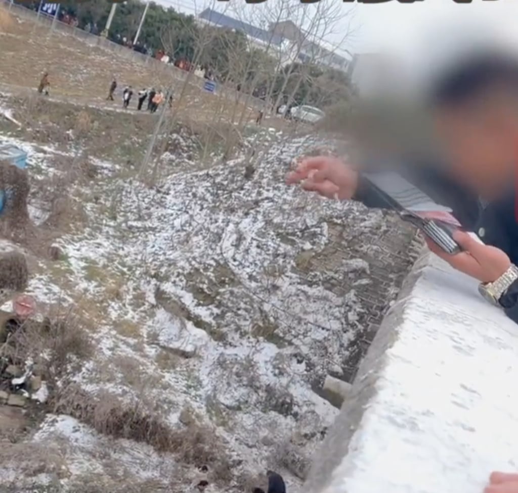 A man throws banknotes off a bridge in the hope that it will prevent calamity from befalling him. Photo: Weibo A man throws banknotes off a bridge in the hope that it will prevent calamity from befalling him. Photo: Weibo