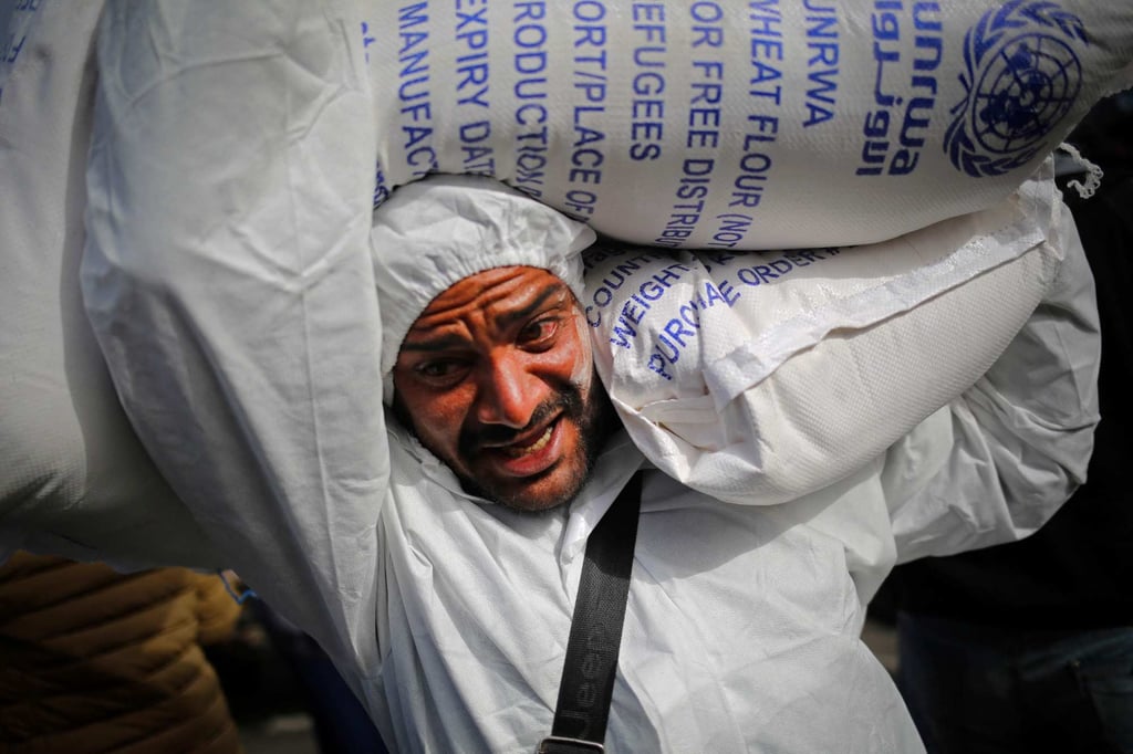A Palestinian man carries sacks of humanitarian aid at a UNRWA distribution centre in Rafah in the southern Gaza Strip. Photo: AFP A Palestinian man carries sacks of humanitarian aid at a UNRWA distribution centre in Rafah in the southern Gaza Strip. Photo: AFP