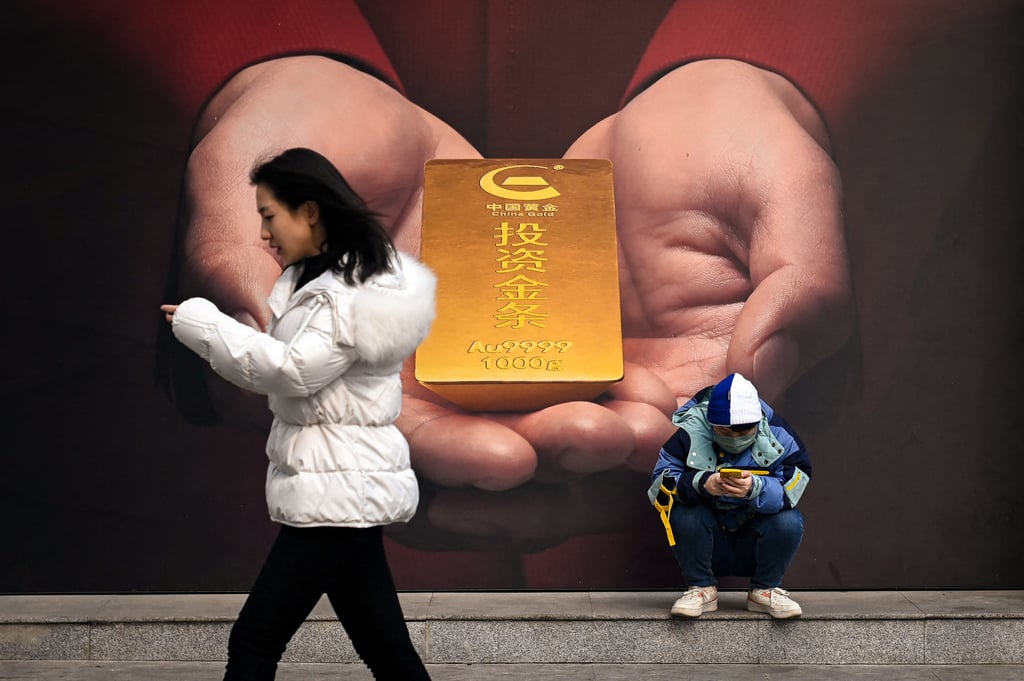 A man uses his mobile phone in front of a poster of gold along a street in Beijing on February 27, 2024. Photo: AFP A man uses his mobile phone in front of a poster of gold along a street in Beijing on February 27, 2024. Photo: AFP