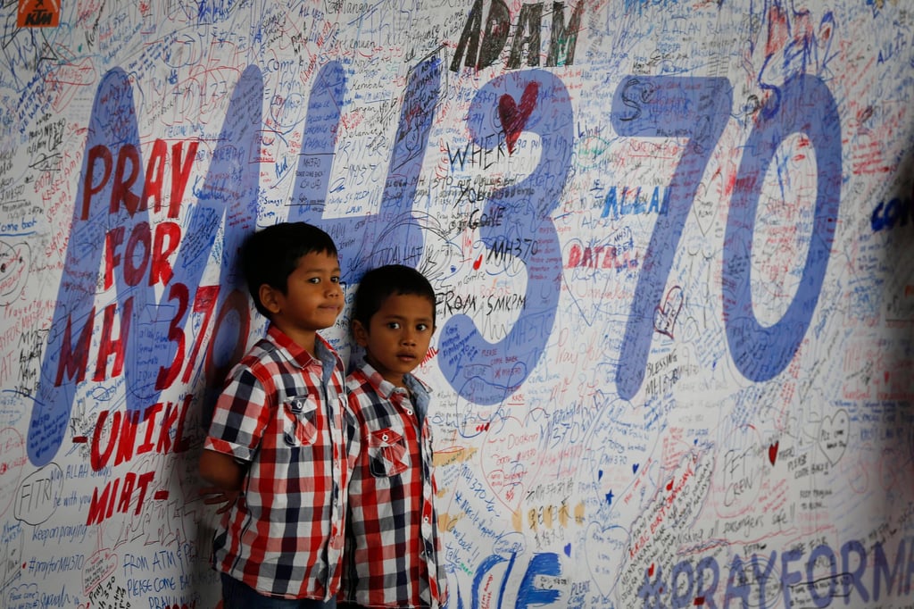 Two Malaysian children stand in front of a message board with well wishes on it to people involved with the missing MH370, in Sepang, Malaysia, on March 16, 2014. Photo: AP Two Malaysian children stand in front of a message board with well wishes on it to people involved with the missing MH370, in Sepang, Malaysia, on March 16, 2014. Photo: AP